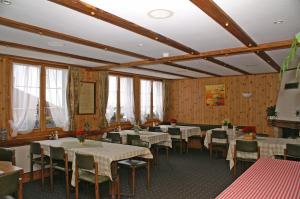 a dining room with tables and chairs and wooden walls at Pension Sonne in Adelboden