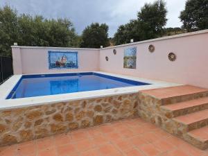 a swimming pool with a stone retaining wall and stairs at Casa Dehesa La Lancha in Cumbres Mayores