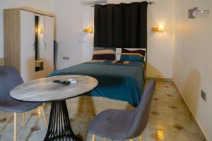 a bedroom with a bed and a wooden table and chairs at STUDIO East Legon, Adjiringanor in Ogbojo