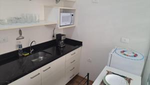 een kleine keuken met een spoelbak en een magnetron bij Flat Centro de Curitiba Rua 24 horas in Curitiba