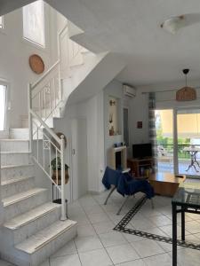 a white living room with stairs and a table at Olivia sea side house in Hanioti