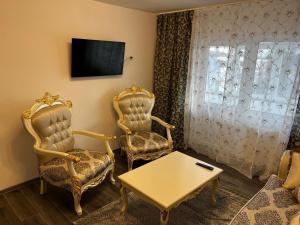 a living room with two chairs and a table and a tv at Apartament 2 camere in Roman