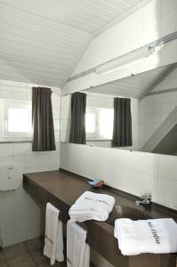 y baño con lavabo, espejo y toallas. en Hotel Restaurant D'Hofstee en Zuienkerke