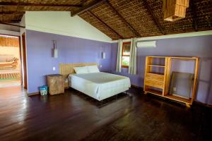 a bedroom with a bed and a wooden floor at Refugio pe na areia na Praia do Acuipe com Wi-Fi in Olivença