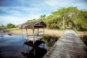 a wooden dock with a hut on the water at Refugio pe na areia na Praia do Acuipe com Wi-Fi in Olivença