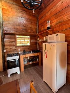 a kitchen with a refrigerator and a stove at Cabana Pôr-do-sol in Torres +12 photos