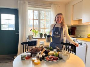 a woman standing in a kitchen with a table of food at Ales BnB in Löderup