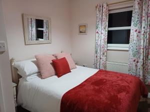 a bedroom with a large white bed with red pillows at Central Ripon - Sleeps 3 - Garden - Pet Friendly in Ripon