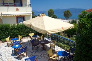 un patio avec une table, des chaises et un parasol dans l'établissement Kalypso Studios & Apartments, à Karavomylos