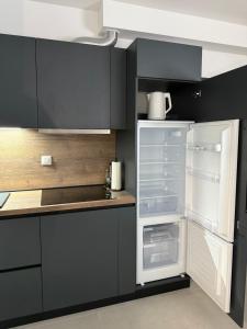 an empty refrigerator in a kitchen with black cabinets at Dalma Pro Apartments - Cozy Studio & Spacious One-Bedroom Apartment - Self Check-in in Karlovac