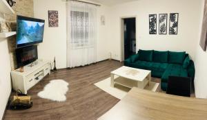 un soggiorno con un divano verde e una TV di Apartment under the High Tatras a Mlynica