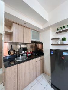 a kitchen with a sink and a black refrigerator at Apartemen Podomoro Golf View BY ID ROOM in Tjikuda Tiga
