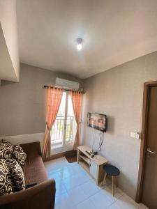 a living room with a couch and a window at Apartemen Podomoro Golf View BY ID ROOM in Tjikuda Tiga