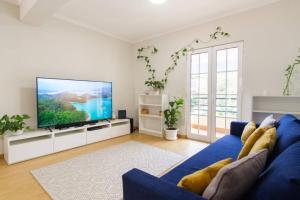 Una sala de estar con un sofá azul y un televisor de pantalla plana. en Brava Home - Best Location to Explore Madeira, en Ribeira Brava