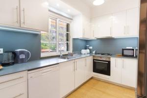 una cocina con armarios blancos y una pared azul en Brava Home - Best Location to Explore Madeira, en Ribeira Brava