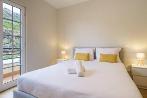 1 dormitorio blanco con 1 cama blanca grande con almohadas amarillas en Brava Home - Best Location to Explore Madeira, en Ribeira Brava