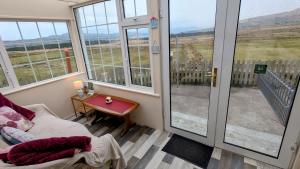 a room with a view of a balcony with a table at Skellig View Harbour View Sunrise Apartment in Portmagee