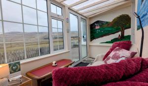 a room with a couch and a table and windows at Skellig View Harbour View Sunrise Apartment in Portmagee