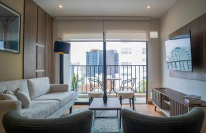 a living room with a couch and chairs and a balcony at Aguirre By Wynwood House in Lima