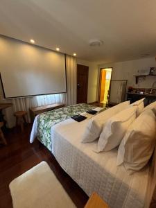 a bedroom with a large white bed with a large screen at Miradouro São Pedro da Serra in São Pedro da Serra