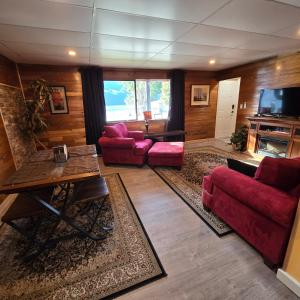 a living room with red couches and a tv at Ocean's Edge in Port Alice