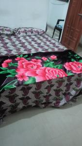 ein Bett mit einer Decke mit rosa Blumen drauf in der Unterkunft Star hostel 3 km from sangam in Prayagraj