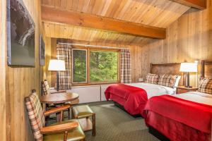a bedroom with two beds and a desk and a table at Glacier Bay Lodge in Gustavus