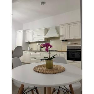 a white kitchen with a white table with a flower on it at Salento Apartment in Brindisi