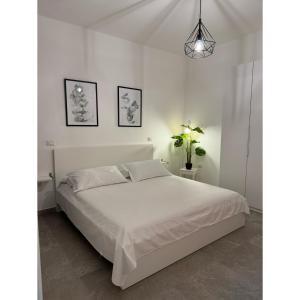 a white bedroom with a bed and a potted plant at Salento Apartment in Brindisi