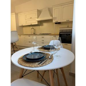 a white table with glasses and plates on it at Salento Apartment in Brindisi