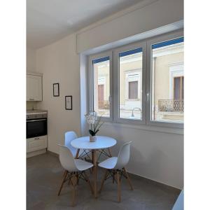 a dining room with a table and chairs and windows at Salento Apartment in Brindisi