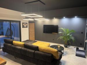 a living room with a couch and a flat screen tv at Maison Moderne piscine chauffée in Saint-Hilaire-de-Brethmas