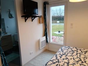 a bedroom with a bed and a tv and a window at Les hortensias in Soubran