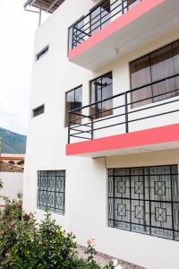 a white building with red accents and windows at Hostal Santa Rosa in Caraz