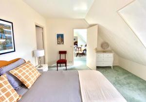 a white bedroom with a bed and a chair at Duplex Bellevue, vue mer, à 50m de la plage! in Réville