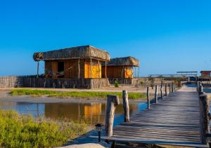 a wooden boardwalk leading to two huts on the beach at Palaa Mayapo Ecolodge in Mayapo