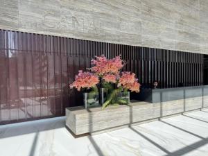 a vase filled with pink flowers in front of a building at Harbor Row in Manama