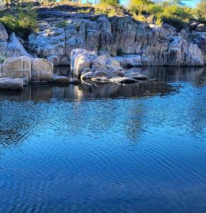 a body of water with rocks and blue water at Posada Entre Dos in Mina Clavero