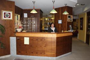a woman is standing behind a counter in a bar at Hotel Tre Denti in Cantalupa