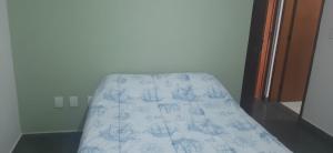 a bed with a blue and white sheet on it at Apartamento Relax Enseada Bertioga SP in Bertioga