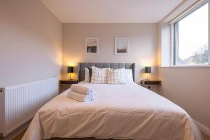 a bedroom with a large white bed with two lamps at 3rd Floor Stylish 2-Bed Apartment in Drogheda