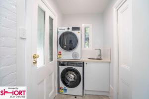 a washing machine in a kitchen next to a door at King & Queen Bed - Apartment on Summer Near Cook Park in Orange