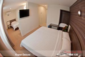 a hotel room with a bed and a tv at De Spring Hotel in Kuantan