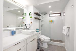a white bathroom with a sink and a toilet at Waikiki Banyan Fabulous Ocean View Condo with Free Parking in Honolulu