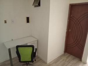 una sedia verde in una stanza con scrivania e porta di Casinha Duplex na Avenida Centenário com varanda, Ar e Wi-Fi a Salvador