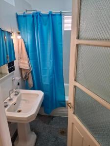 a bathroom with a blue shower curtain and a sink at Encanto en el centro salteño in Salta