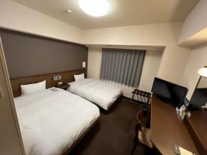 a hotel room with two beds and a television at Hotel Route-Inn Uozu in Uozu