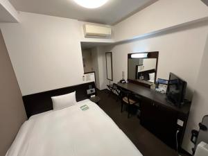 a bedroom with a bed and a desk and a mirror at Hotel Route-Inn Uozu in Uozu