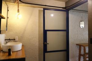 a bathroom with a door leading to a sink at Los Cruxes in Tepoztlán