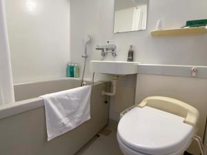 a bathroom with a toilet and a sink and a tub at Hotel Route-Inn Uozu in Uozu